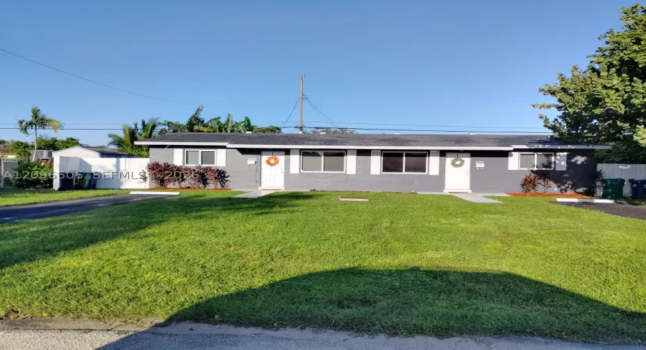 Duplex residence featuring a gray exterior, white trim, and a shingle roof