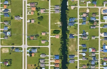 Vacant residential lot featuring direct canal access, established tree canopy, and road frontage