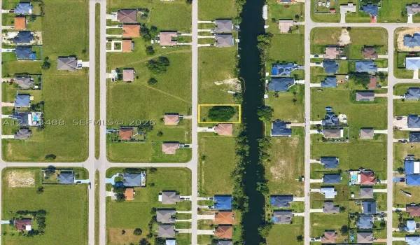 Vacant residential lot featuring direct canal access, established tree canopy, and road frontage