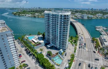 High-rise residential tower featuring floor-to-ceiling glass paneling, private balconies, an elevated swimming pool, and an onsite water feature