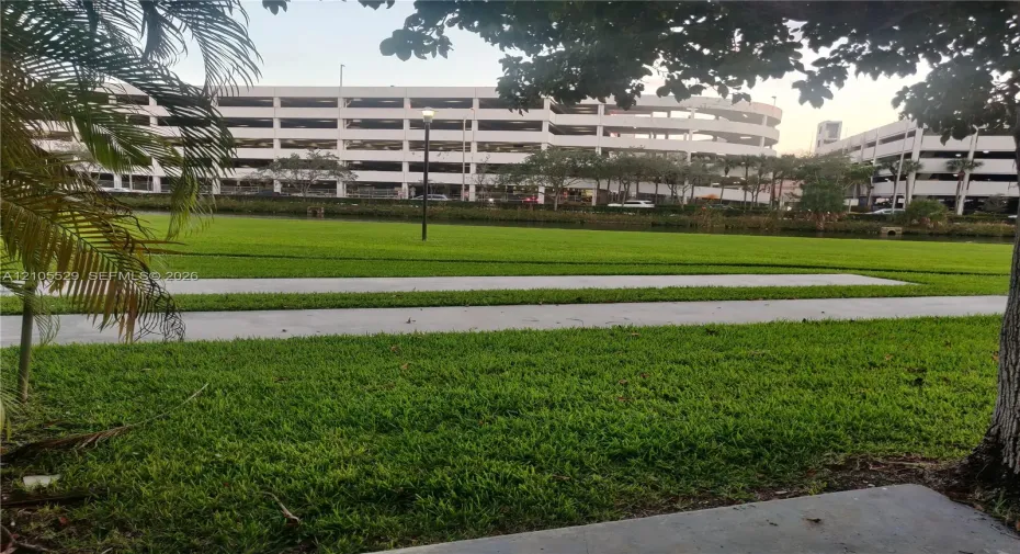 Expansive green space featuring manicured lawns, paved pathways, and mature trees