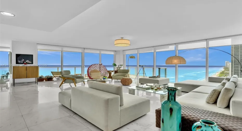 Elegant living area featuring Carrara marble flooring, floor-to-ceiling windows, stunning ocean views, and recessed ceiling lighting.
