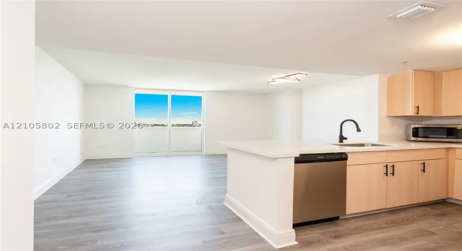 Kitchen featuring light-finish cabinetry, stone-surface countertops, stainless steel appliances, a matte black faucet, and wood-finish flooring