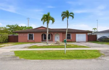 Mediterranean-style home featuring a terracotta tile roof, arched entryway, and dual palm trees