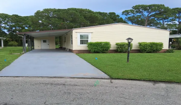 Light-colored siding exterior with a covered carport and paved driveway