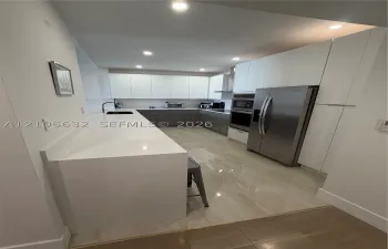 Kitchen featuring flat-panel cabinetry, stone countertops, stainless steel appliances, built-in double wall ovens, and tile flooring
