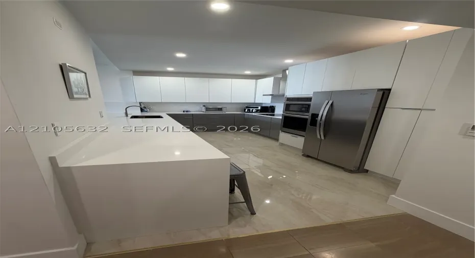 Kitchen featuring flat-panel cabinetry, stone countertops, stainless steel appliances, built-in double wall ovens, and tile flooring