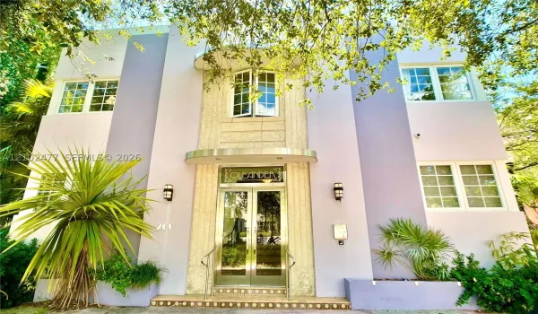 Art Deco architectural facade featuring vertical masonry detailing, symmetrical multi-pane windows, arched entry hood, and glass-paneled double doors
