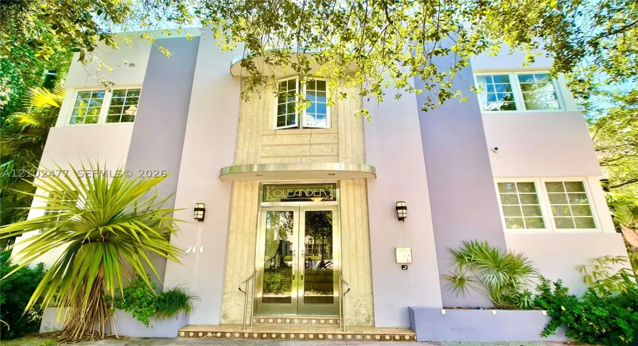 Art Deco architectural facade featuring vertical masonry detailing, symmetrical multi-pane windows, arched entry hood, and glass-paneled double doors