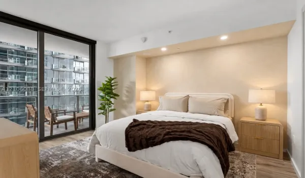 Floor-to-ceiling sliding glass door, recessed lighting, textured accent wall, wood-finish flooring, and private balcony