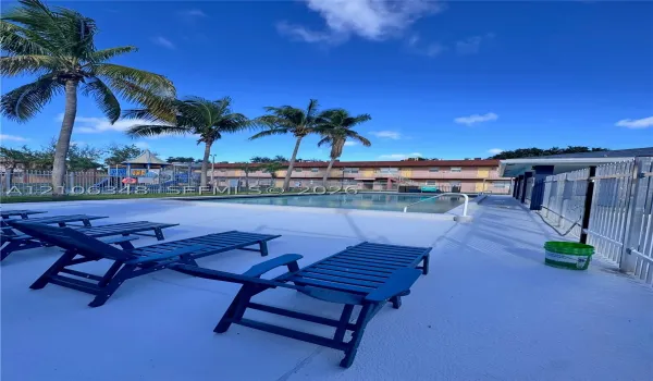 In-ground swimming pool featuring a concrete deck and metal perimeter fencing, accented by mature palm trees