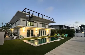 Multi-level exterior featuring a private in-ground pool, expansive rooftop deck with cable railings, integrated spiral staircase, and exterior wall-mounted lighting