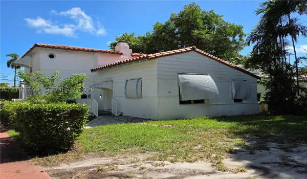 Spanish Colonial architecture featuring a clay tile roof, light-toned exterior finish, and metal window awnings