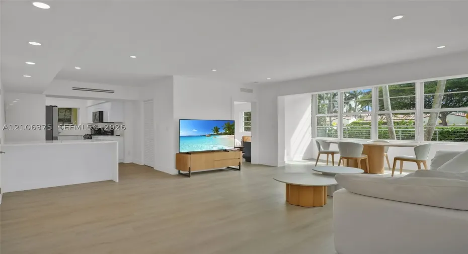 Open-concept interior featuring light wood-finish flooring, recessed lighting, and large windows with horizontal muntins