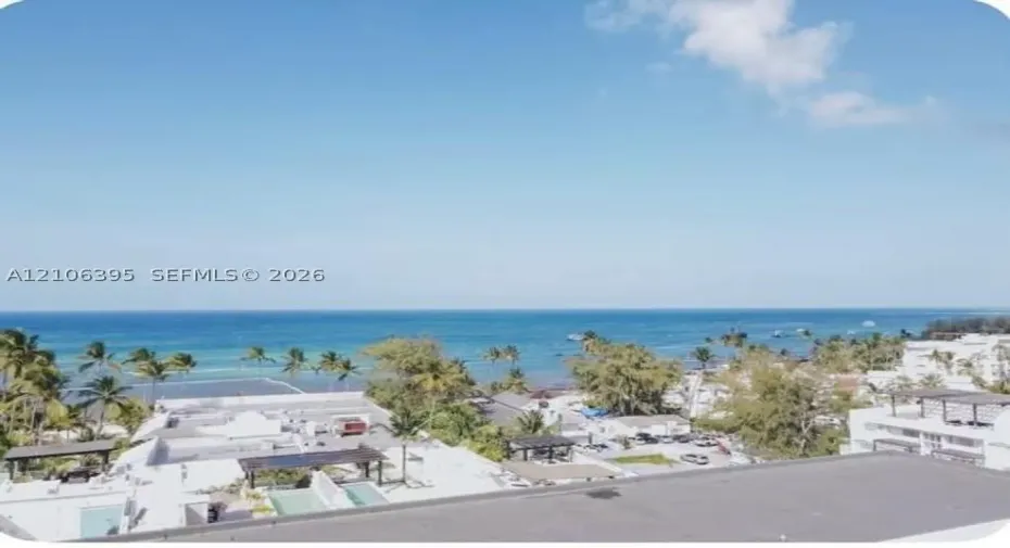 Elevated perspective overlooking the coastline, featuring expansive ocean scenery, mature tropical vegetation, and surrounding coastal structures