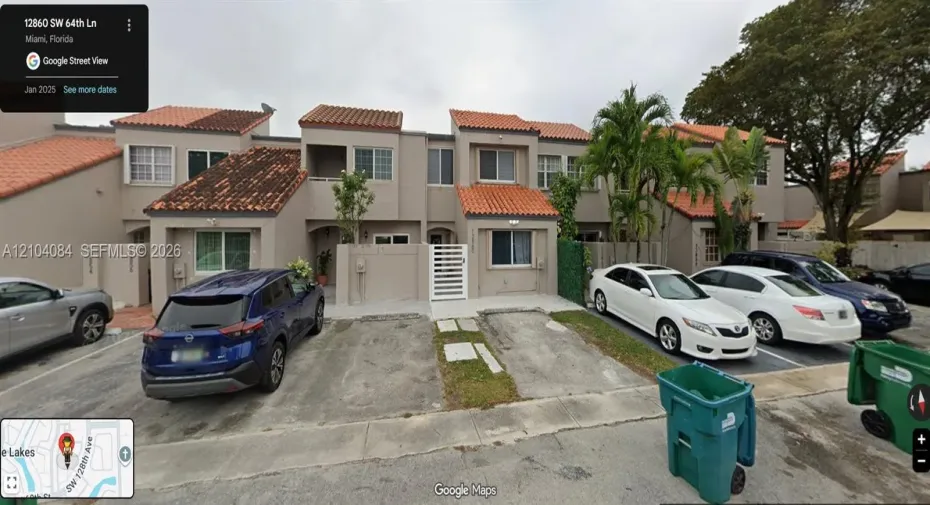 Two-story exterior featuring a clay tile roof, stucco facade, private gated courtyard entry, and dedicated concrete parking pads