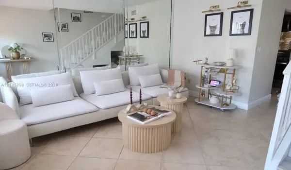 Mirrored accent wall, light tile flooring, white staircase with railing, white baseboards, and a white interior wall