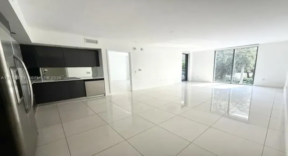 Large-format tile flooring, flat-panel dark cabinetry, stainless steel appliances, and floor-to-ceiling glass sliding doors