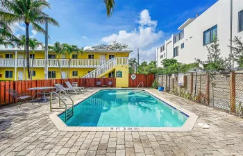 Outdoor swimming pool with integrated entry steps, surrounded by paver patio surfacing, and secured by a perimeter fence