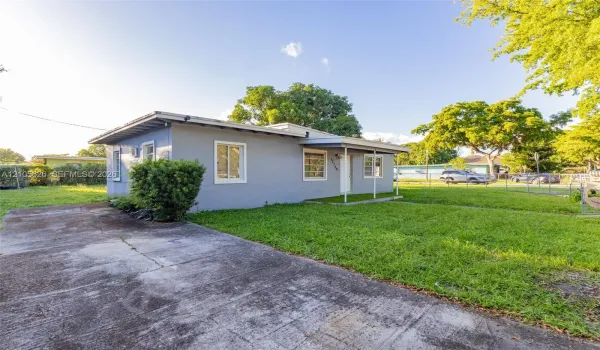 Single-story residence featuring a painted masonry exterior, covered front porch, concrete driveway, and surrounding lawn space