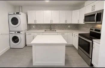 Kitchen featuring white shaker-style cabinetry, a central island with a solid surface countertop, stainless steel appliances, stone-look tile backsplash, and ceramic floor tiling
