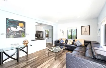 Open-concept interior featuring wood-finish flooring, recessed lighting, and a kitchen pass-through with a dark solid-surface countertop