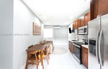 Kitchen featuring cherry-toned cabinetry, stainless steel appliances, a gooseneck faucet, tile flooring, and a wall-mounted climate control unit
