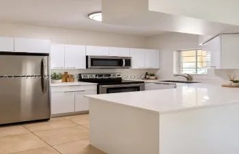 Kitchen featuring high-gloss white cabinetry, quartz countertops, stainless steel appliances, dual-basin stainless steel sink, and large-format tile flooring