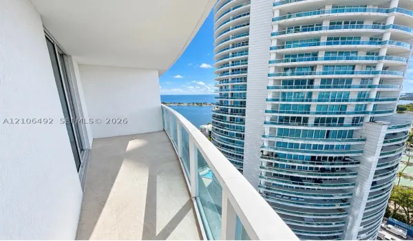 Private balcony featuring neutral tile flooring, glass panel railings, and water scenery