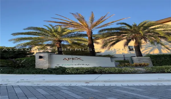 Property entrance featuring stone masonry pillars, integrated lighting fixtures, and native palm tree landscaping