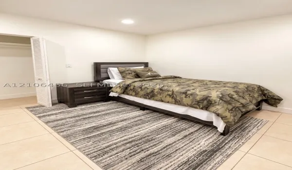 Neutral-toned room featuring ceramic tile flooring, recessed lighting, and a closet with white louvered bifold doors