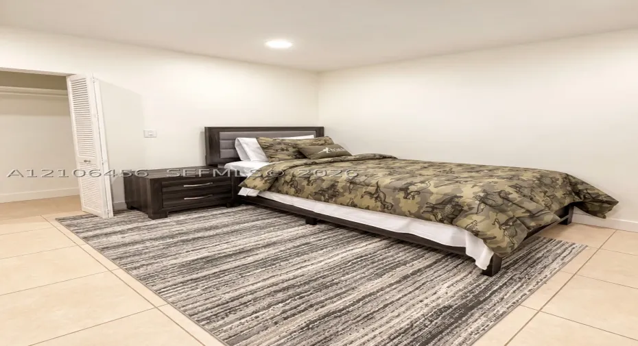 Neutral-toned room featuring ceramic tile flooring, recessed lighting, and a closet with white louvered bifold doors
