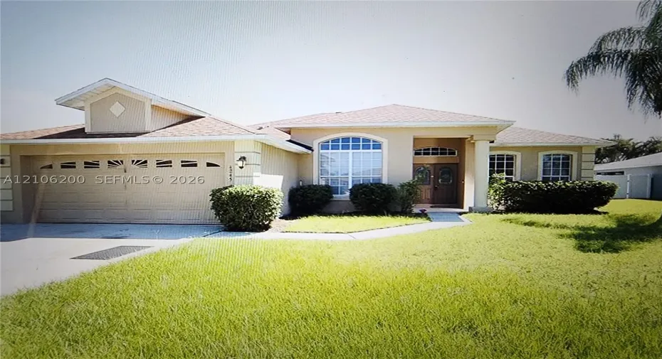 Stucco exterior featuring a multi-gable roofline, arched front window with decorative muntins, double-door entryway, and integrated two-car garage