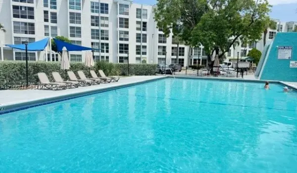 Community swimming pool featuring a concrete deck, tiled perimeter, and blue fabric sun shades