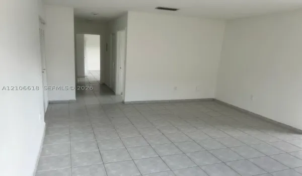 Neutral interior space featuring ceramic tile flooring, solid-wall construction, and multiple doorways
