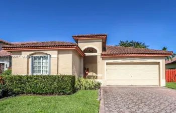 Single-story residence featuring a tile roof, stucco exterior, arched entryway, and a paved stone driveway
