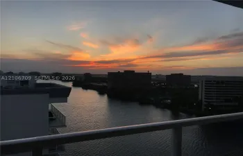 Elevated balcony with a horizontal railing overlooking a waterway and the horizon at dusk