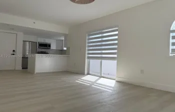 Open-concept kitchen featuring stainless steel appliances, white cabinetry, and a peninsula, complemented by wood-finish flooring and dual-tone window shades