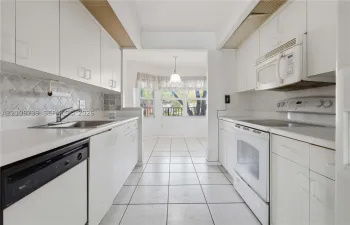 Kitchen featuring white cabinetry, solid-surface countertops, tile backsplash, built-in appliances, and ceramic tile flooring