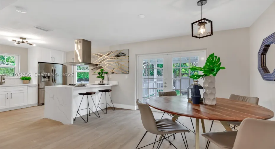 Kitchen featuring a waterfall island with a white stone-finish countertop, stainless steel range hood, built-in stainless steel refrigerator, white cabinetry, and wood-finish flooring