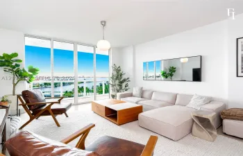 Floor-to-ceiling glass windows, exterior balcony with railing, pendant globe lighting, and polished flooring
