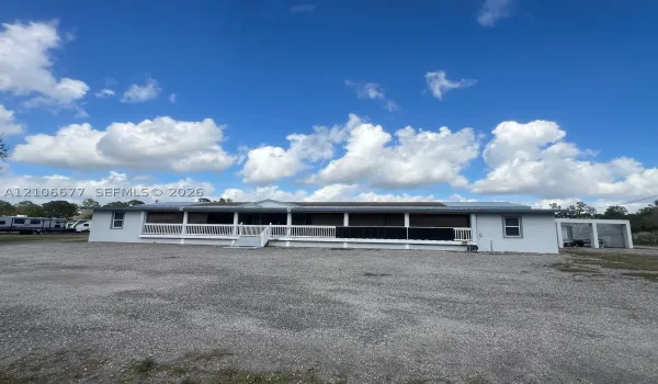 Exterior featuring a full-length covered front porch with white railing, metal roofing, and an attached multi-bay carport