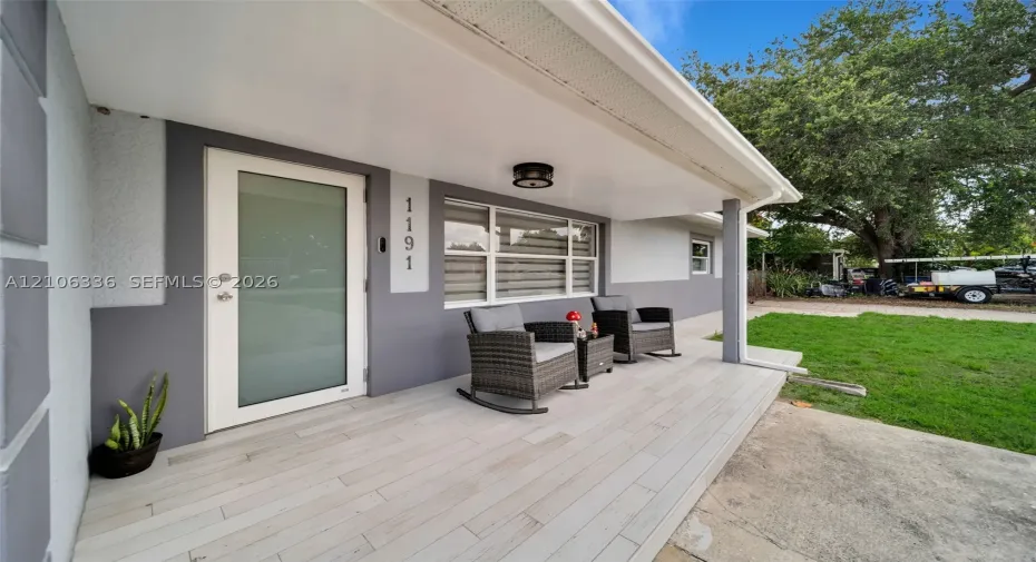 Covered front porch featuring wood-finish tile flooring, a modern glass-panel entry door, and recessed lighting