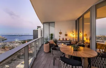 Covered balcony featuring wood-finish flooring, a glass panel railing, and expansive floor-to-ceiling windows