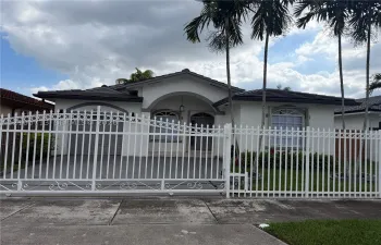 Single-story residence featuring a gated entry, arched front porch, tile roof, arched windows, and mature palm trees
