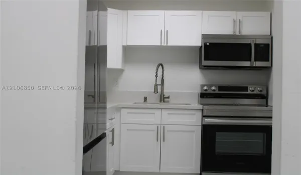 Kitchenette featuring white Shaker-style cabinetry, stainless steel appliances, a stone-composite countertop, and a gooseneck faucet
