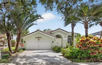 Exterior facade featuring a 2022 tile roof, arched entryway with double doors, arched window detailing, two-car garage, and mature landscaping