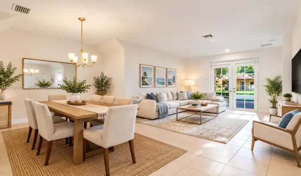 Virtually Stage - Open-concept area featuring high vaulted ceilings, large-format tile flooring, a brass-finish chandelier, and glass-paned French doors