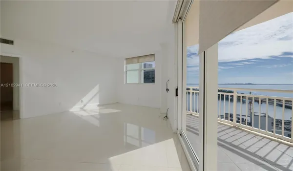 Interior space featuring polished tile flooring, full-height sliding glass doors, and a private balcony with metal railing