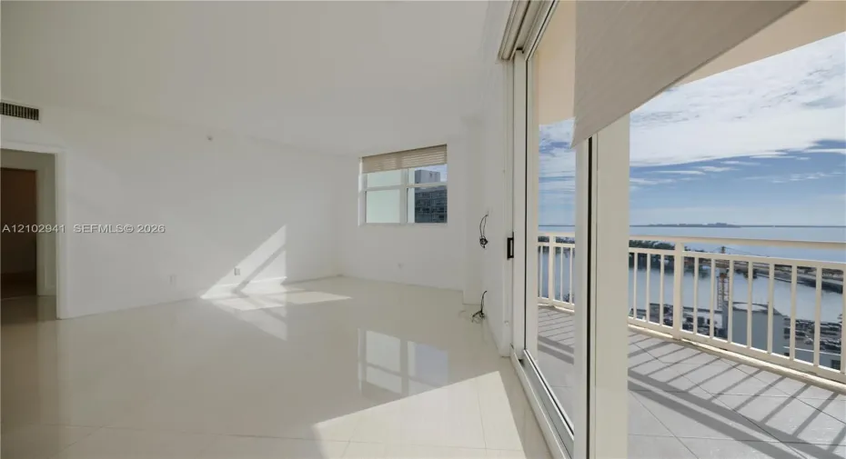Interior space featuring polished tile flooring, full-height sliding glass doors, and a private balcony with metal railing